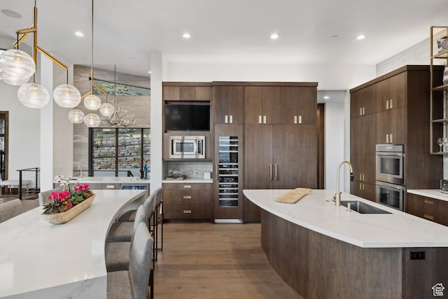 1703 N Chimney Rock Rd Unit 532, Heber City, UT 84032 - kitchen with appliances with stainless steel finishes, a sink, light wood-style flooring, a center island with sink, and light stone countertops