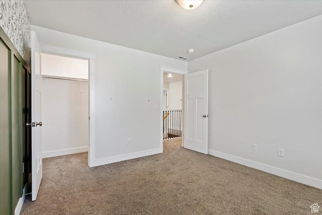 290 N 100 W, Morgan, UT 84050 - unfurnished bedroom with carpet flooring, baseboards, a closet, a textured ceiling, and a walk in closet