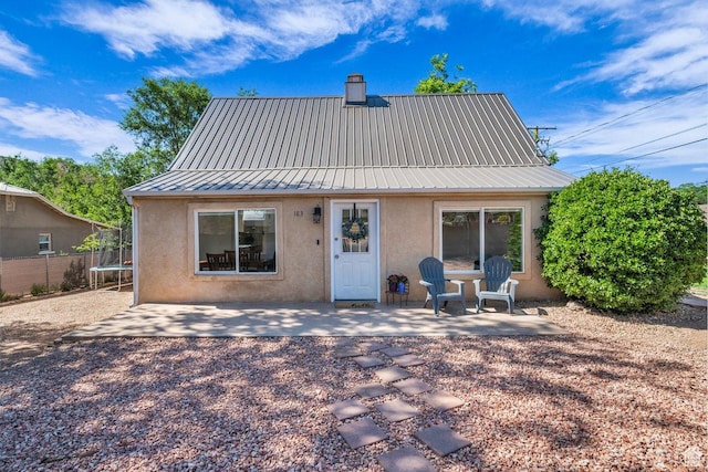 183 W 200 N, Hurricane, UT 84737 - rear view of property featuring a trampoline, stucco siding, a patio area, metal roof, and a chimney