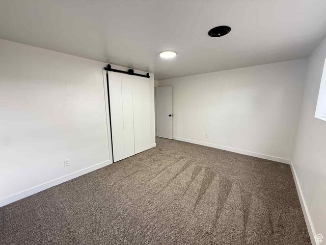 1698 Kenilworth Rd, Helper, UT 84526 - unfurnished bedroom with a barn door, carpet flooring, baseboards, and a closet