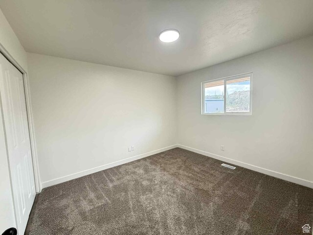 1698 Kenilworth Rd, Helper, UT 84526 - unfurnished bedroom featuring dark carpet, baseboards, and a closet