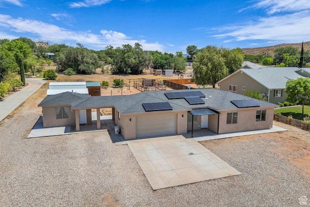 40 W Pecan Ln, Leeds, UT 84746 - view of front of house featuring an attached garage, driveway, roof mounted solar panels, stucco siding, and a shingled roof
