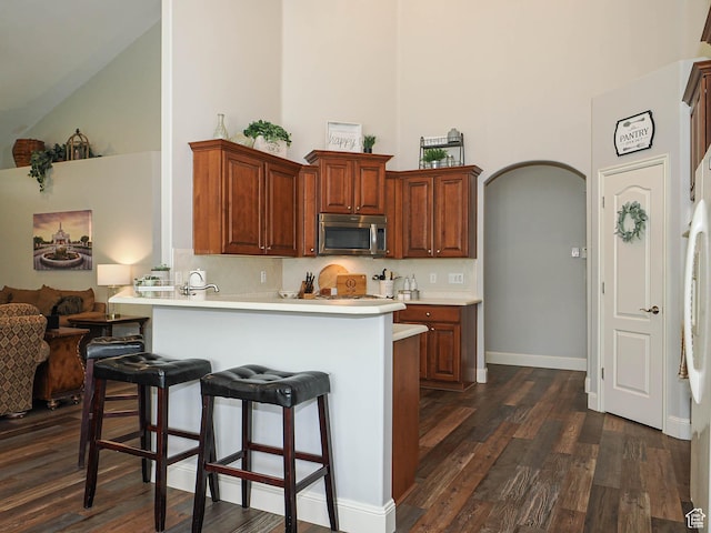 12687 S Verona Creek Way W, Riverton, UT 84065 - kitchen with stainless steel microwave, high vaulted ceiling, a kitchen breakfast bar, dark wood-style flooring, and light countertops