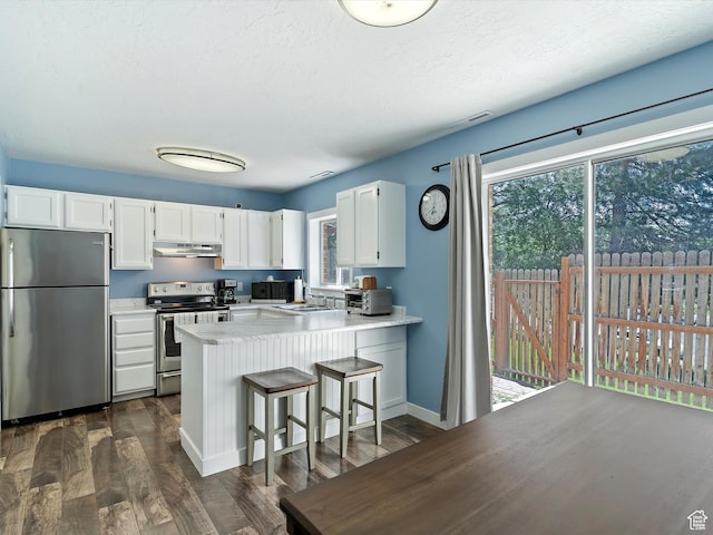 1631 E 1470 S Unit 5E, Ogden, UT 84404 - kitchen featuring appliances with stainless steel finishes, under cabinet range hood, a peninsula, white cabinetry, and a textured ceiling
