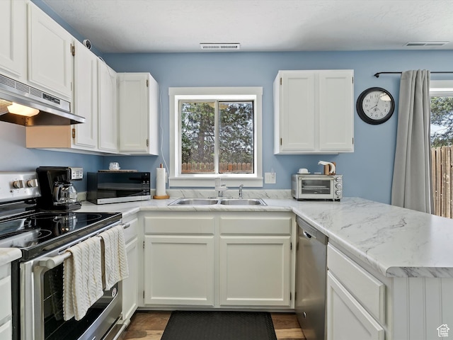 1631 E 1470 S Unit 5E, Ogden, UT 84404 - kitchen with appliances with stainless steel finishes, a sink, under cabinet range hood, white cabinetry, and a peninsula