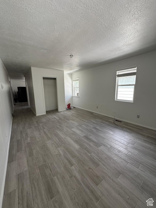 410 Rose Ave, Price, UT 84501 - unfurnished living room with plenty of natural light, a textured ceiling, wood finished floors, and baseboards