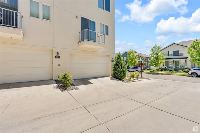 6202 W Birch Run Rd, South Jordan, UT 84009 - view of property exterior with an attached garage, stucco siding, driveway, a balcony, and a residential view