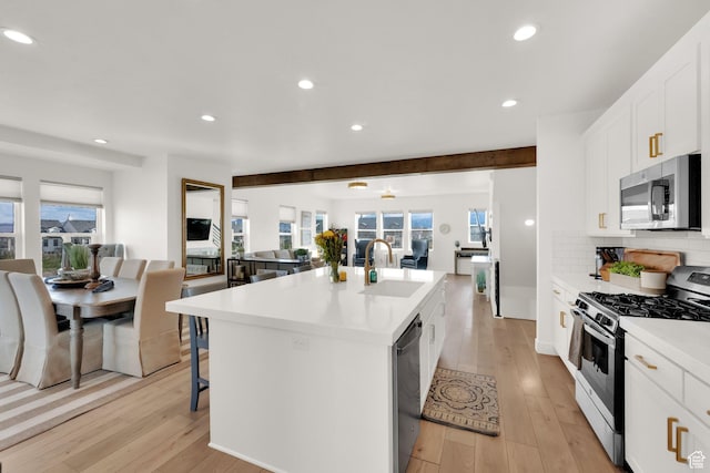 10777 S Lamond Dr W, South Jordan, UT 84009 - kitchen featuring appliances with stainless steel finishes, open floor plan, a sink, a center island with sink, and light wood-style floors