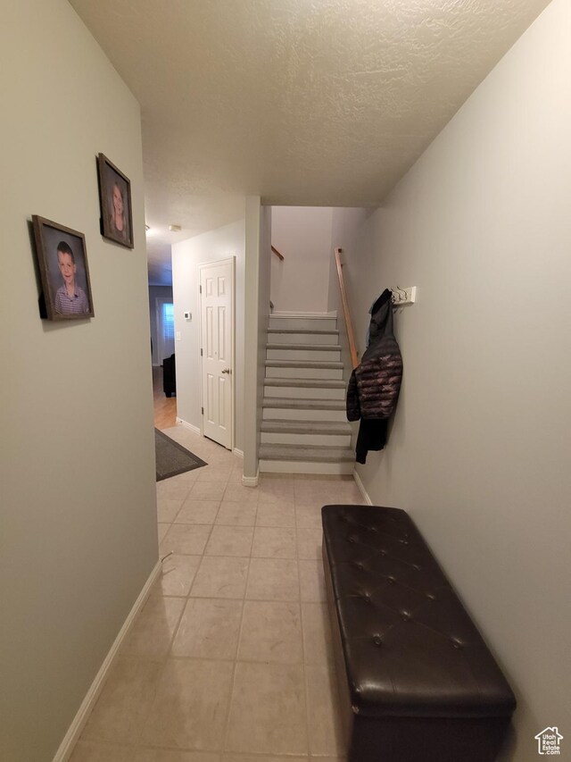 3878 W Sage Willow Dr, South Jordan, UT 84009 - corridor with stairway, a textured ceiling, light tile patterned flooring, and baseboards