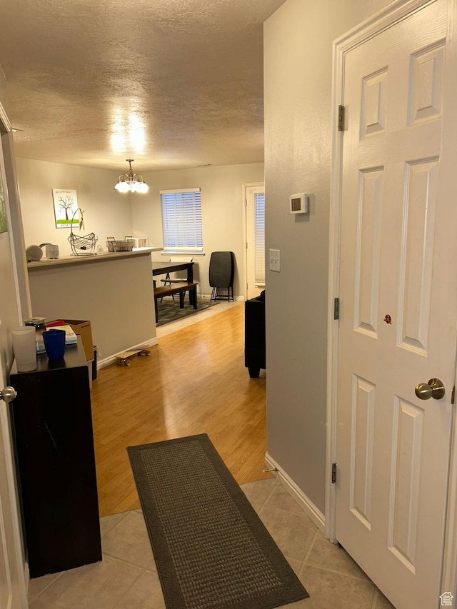 3878 W Sage Willow Dr, South Jordan, UT 84009 - hall featuring a textured ceiling, baseboards, light tile patterned floors, and a chandelier