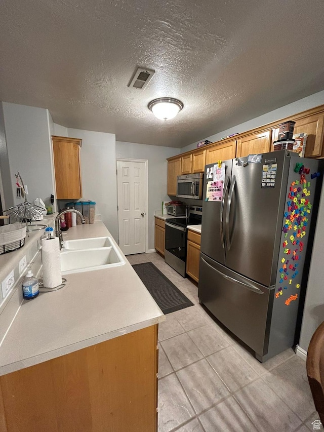 3878 W Sage Willow Dr, South Jordan, UT 84009 - kitchen with appliances with stainless steel finishes, a sink, brown cabinetry, light countertops, and a textured ceiling