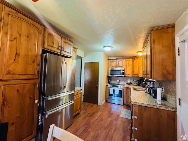 2557 W 5725 S, Roy, UT 84067 - kitchen featuring appliances with stainless steel finishes, a sink, dark wood-style flooring, brown cabinetry, and light countertops