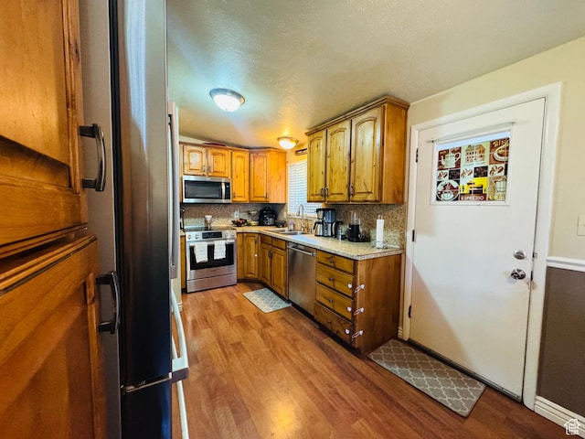 2557 W 5725 S, Roy, UT 84067 - kitchen with stainless steel appliances, brown cabinetry, wood finished floors, decorative backsplash, and a textured ceiling