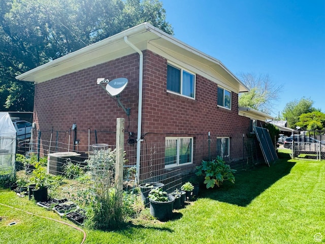 2557 W 5725 S, Roy, UT 84067 - view of side of home with central AC unit, brick siding, a greenhouse, a vegetable garden, and an outdoor structure