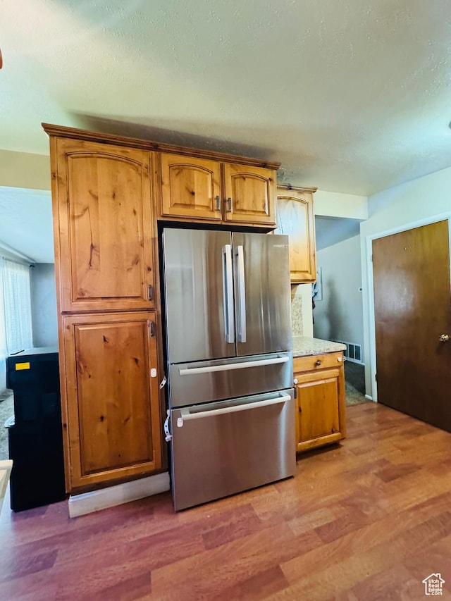 2557 W 5725 S, Roy, UT 84067 - kitchen featuring freestanding refrigerator, light wood finished floors, light countertops, and brown cabinets