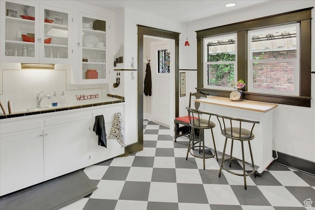 623 E Milton Ave, Salt Lake City, UT 84105 - kitchen featuring tile patterned floors, tile counters, white cabinets, tasteful backsplash, and glass insert cabinets