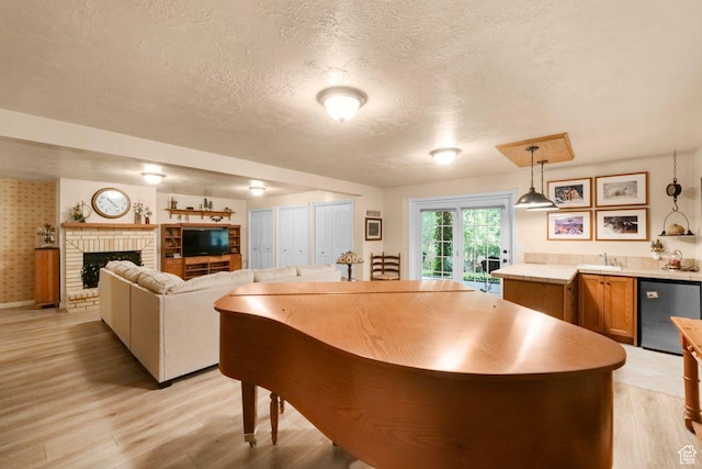 1262 W Dusty Downs Cir S, Jordan, UT 84095 - kitchen featuring dishwasher, a textured ceiling, light wood-type flooring, light countertops, and a fireplace