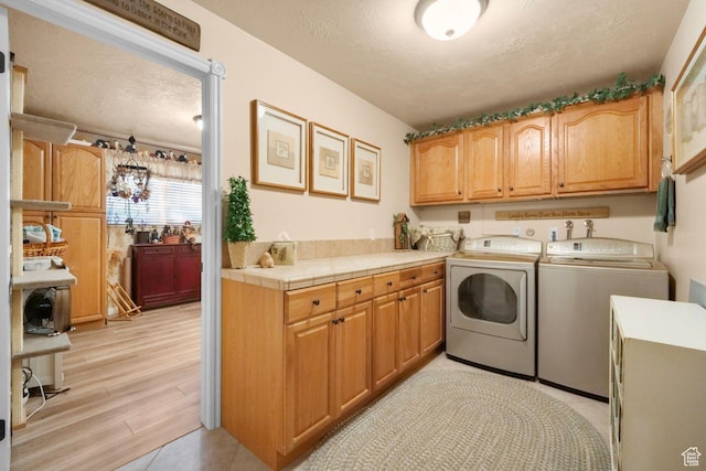 1262 W Dusty Downs Cir S, Jordan, UT 84095 - washroom featuring washing machine and dryer, cabinet space, light wood finished floors, and a textured ceiling