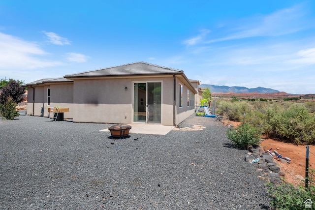 258 N Windsor Dr, Washington, UT 84780 - back of house with an outdoor fire pit, a mountain view, stucco siding, a tile roof, and a patio area