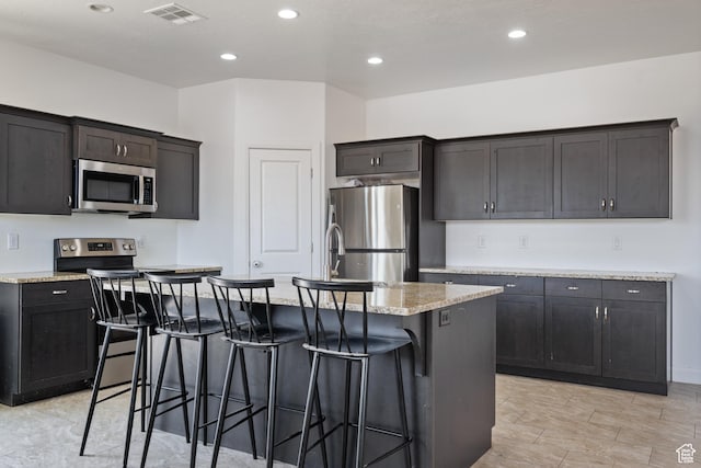 258 N Windsor Dr, Washington, UT 84780 - kitchen featuring appliances with stainless steel finishes, a breakfast bar area, a kitchen island with sink, recessed lighting, and light stone counters