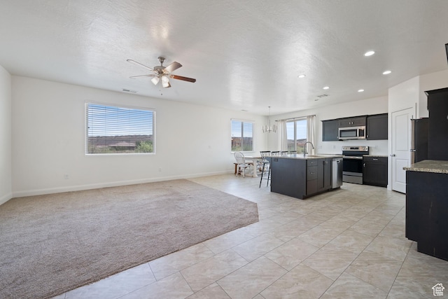 258 N Windsor Dr, Washington, UT 84780 - kitchen featuring stainless steel appliances, dark cabinets, a kitchen island with sink, a ceiling fan, and open floor plan