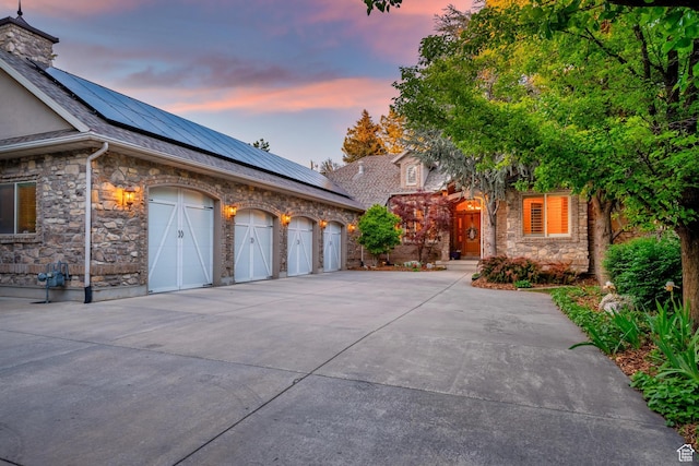 2221 E Fisher Ln S, Salt Lake City, UT 84109 - view of front of home with stone siding, roof mounted solar panels, concrete driveway, and a garage