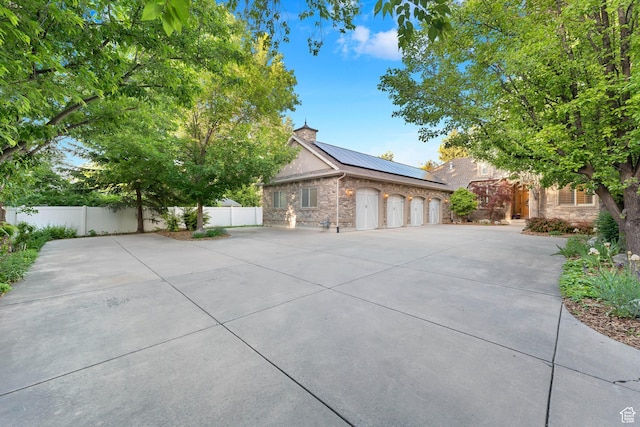 2221 E Fisher Ln S, Salt Lake City, UT 84109 - view of front of property featuring roof mounted solar panels, concrete driveway, stone siding, and a standing seam roof