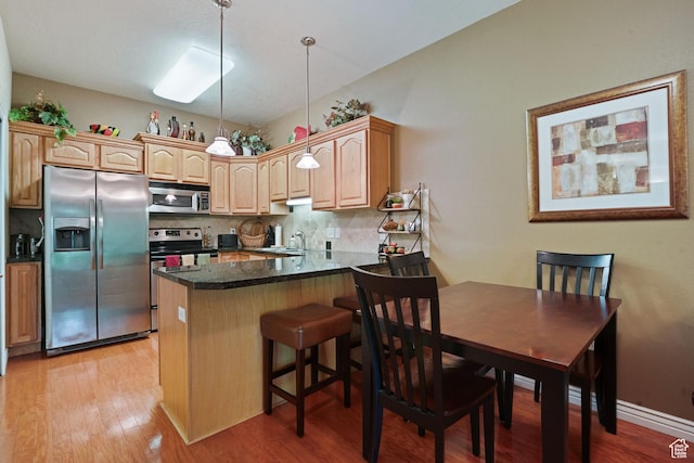 1174 E 3300 S Unit 417, Millcreek, UT 84106 - kitchen with stainless steel appliances, tasteful backsplash, a peninsula, and light wood-style floors