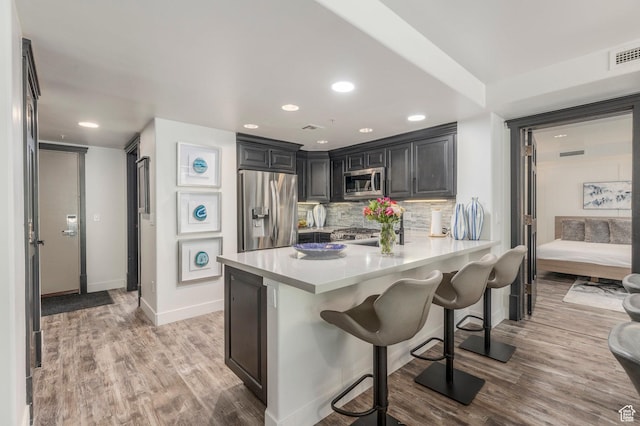 2900 Deer Valley Dr E Unit E211, Deer Valley, UT 84060 - kitchen with appliances with stainless steel finishes, light wood-type flooring, light countertops, a kitchen breakfast bar, and decorative backsplash