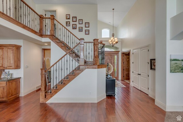 6663 W Normandy Way, Highland, UT 84003 - foyer entrance with high vaulted ceiling, wood-type flooring, stairs, a chandelier, and baseboards