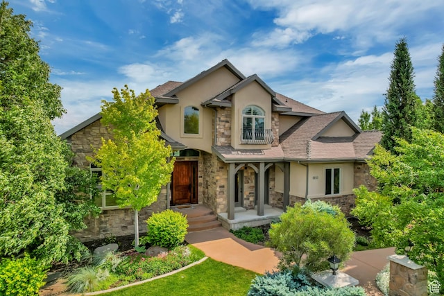 6663 W Normandy Way, Highland, UT 84003 - view of front of house featuring stone siding, stucco siding, a balcony, and covered porch