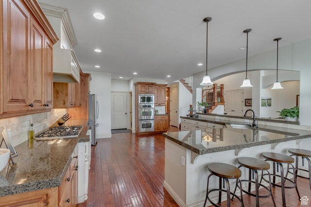 6663 W Normandy Way, Highland, UT 84003 - kitchen with appliances with stainless steel finishes, a sink, decorative backsplash, a kitchen breakfast bar, and dark wood-style flooring
