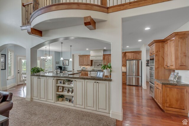 6663 W Normandy Way, Highland, UT 84003 - kitchen featuring appliances with stainless steel finishes, arched walkways, a high ceiling, light wood-style flooring, and dark stone counters