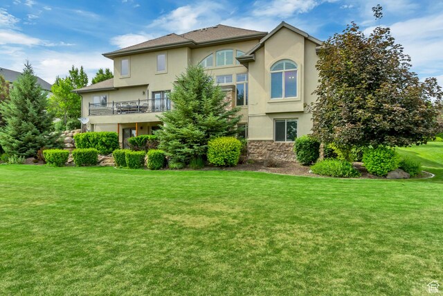 6663 W Normandy Way, Highland, UT 84003 - rear view of house featuring stucco siding, a lawn, a balcony, and stone siding