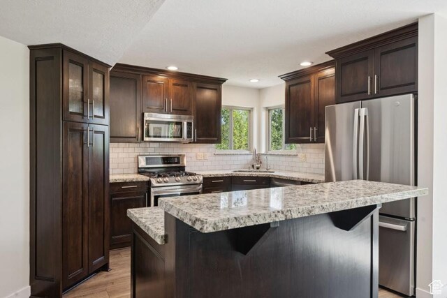8086 N Meadowview Dr, Snyderville, UT 84098 - kitchen featuring appliances with stainless steel finishes, a sink, light wood-style floors, dark brown cabinetry, and backsplash