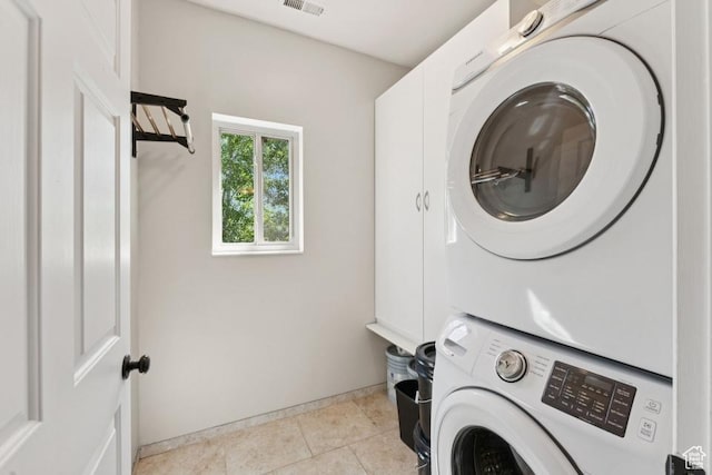 8086 N Meadowview Dr, Snyderville, UT 84098 - washroom featuring stacked washing machine and dryer, cabinet space, baseboards, and light tile patterned floors
