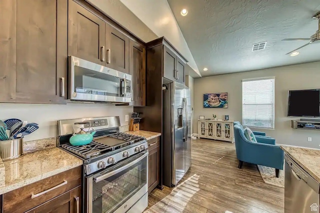1914 E Fiesta Ln, Washington, UT 84780 - kitchen with appliances with stainless steel finishes, light wood-type flooring, dark brown cabinets, light stone countertops, and a textured ceiling