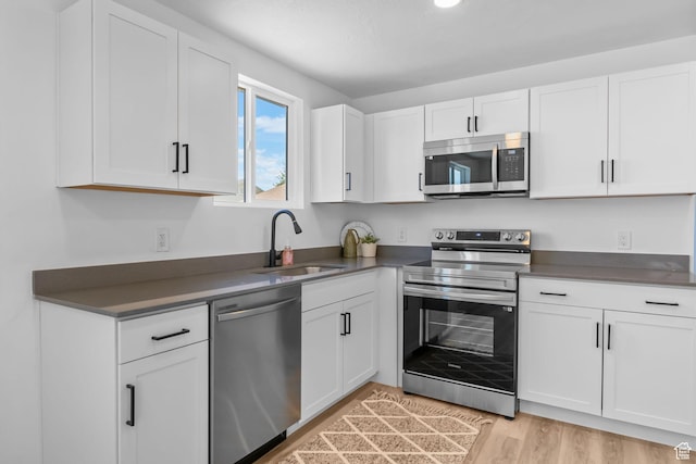 3717 W 8620 S, West Jordan, UT 84088 - kitchen with stainless steel appliances, a sink, white cabinetry, dark countertops, and light wood-type flooring