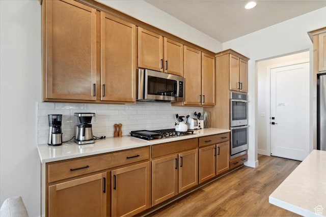 5936 N Angels Landing Dr, Mountain Green, UT 84050 - kitchen with appliances with stainless steel finishes, backsplash, wood finished floors, light countertops, and brown cabinets