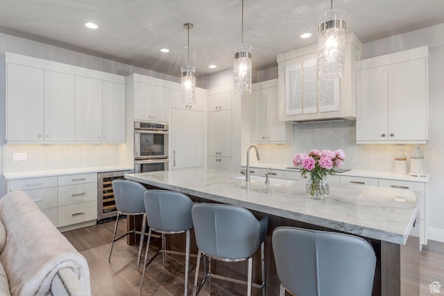 1136 E Black Hawk Way, Hideout, UT 84036 - kitchen featuring double oven, beverage cooler, a sink, a breakfast bar area, and dark wood finished floors