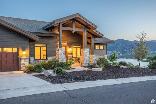 1136 E Black Hawk Way, Hideout, UT 84036 - modern home with stone siding, concrete driveway, a mountain view, roof with shingles, and a garage
