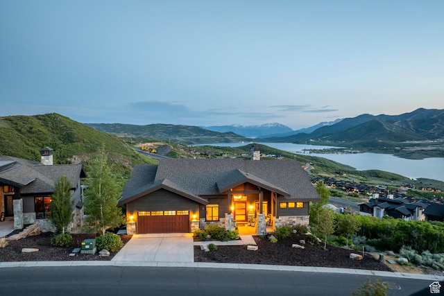 1136 E Black Hawk Way, Hideout, UT 84036 - view of front of house with stone siding, an attached garage, a water and mountain view, concrete driveway, and a shingled roof