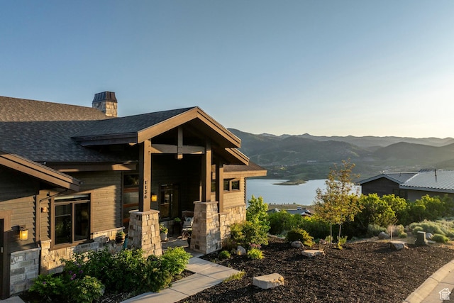 1136 E Black Hawk Way, Hideout, UT 84036 - entrance to property featuring roof with shingles, stone siding, a chimney, and a water and mountain view