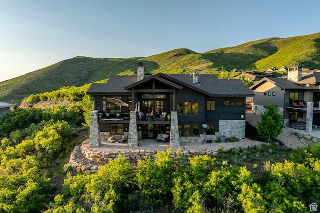 1136 E Black Hawk Way, Hideout, UT 84036 - rear view of house featuring stone siding, a patio area, a balcony, a chimney, and a mountain view