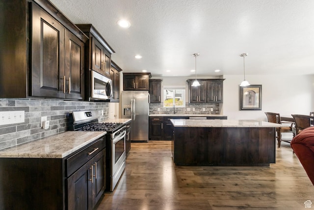 1788 S Longview Rd Unit 161, Santaquin, UT 84655 - kitchen featuring appliances with stainless steel finishes, a center island, dark brown cabinetry, tasteful backsplash, and dark wood-style floors