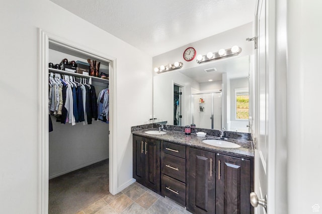 1788 S Longview Rd Unit 161, Santaquin, UT 84655 - bathroom with a stall shower, a walk in closet, double vanity, stone finish floors, and baseboards