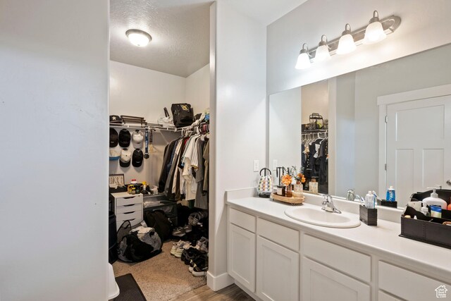 633 N Sun Peak Dr, Vineyard, UT 84059 - bathroom featuring a spacious closet, vanity, and a textured ceiling