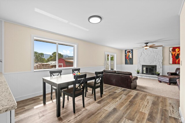 12345 S Redwood Rd, Riverton, UT 84065 - dining area with wainscoting, wood finished floors, ceiling fan, and a fireplace