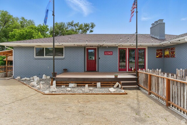 12345 S Redwood Rd, Riverton, UT 84065 - rear view of house with a wooden deck, brick siding, a chimney, and roof with shingles