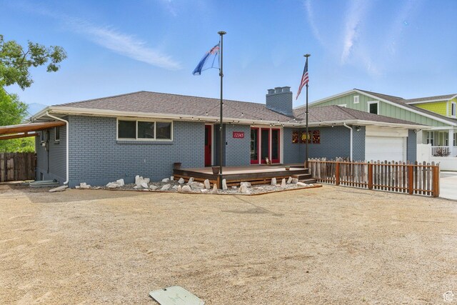 12345 S Redwood Rd, Riverton, UT 84065 - view of front of home featuring a deck, brick siding, an attached garage, a chimney, and driveway